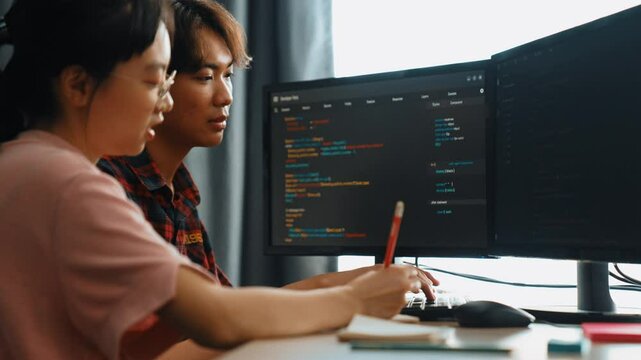 Slow motion back end software developer engineer for computer programming working together on debugging writing computing code, solving complex algorithms display on monitor in office. Burgeoning