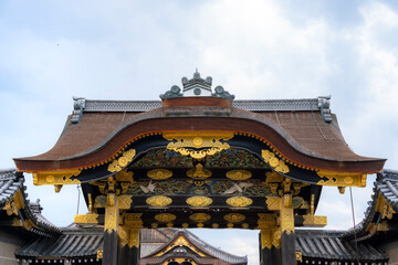 Fototapeta premium A close-up view of the beautifully ornate entrance gate at Nijo Castle in Kyoto, Japan. The gate features intricate gold details and traditional Japanese architectural designs, showcasing the castle's