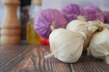 Fresh Garlic Bulbs Accompanied by an Assortment of Herbs on a Rustic Wooden Table Surface