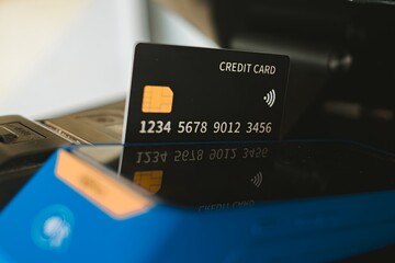 A black credit card inserted into a blue EDC card reader machine with bokeh background