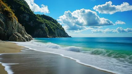 A sandy beach stretches towards a calm, turquoise ocean, framed by a lush green cliff
