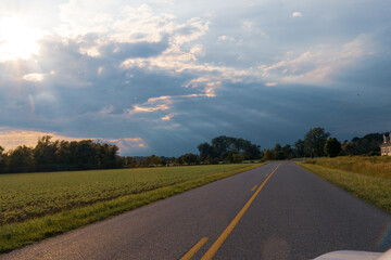 the clouds in the sky open up and shine light down from the heavens above on an open country road trip through America 