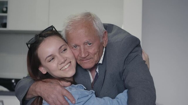 Loving grandfather embracing his happy granddaughter at home