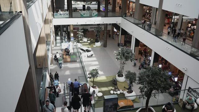 Busy shopping mall atmosphere with diverse crowd and modern design, contemporary architecture, and various retail stores.