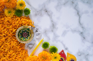 Preparation for Diwali festival decoration with diya clay lamp and flowers on marble floor.