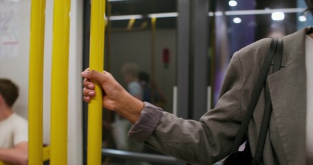 A woman in formal clothes and with earphones is riding in a subway car. She gets out of the carriage when the train stops