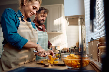 Happy woman chopping pumpkin while making  pie for Thanksgiving dinner.