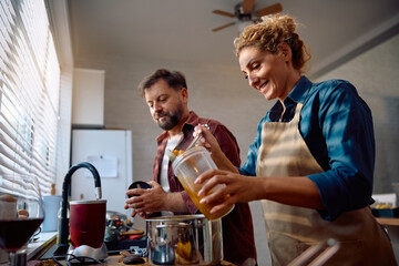 Happy woman and her husband preparing Thanksgiving dinner and cooking in kitchen.