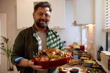 Happy man serving Thanksgiving turkey and looking at camera.