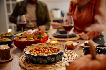 Thanksgiving pumpkin pie on dining table with couple in  background.