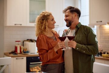 Happy couple toasting with wine in  kitchen.