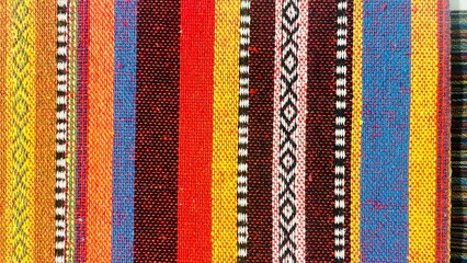 A vibrant woven fabric featuring colorful stripes and intricate patterns, perfect for clothing or home decoration, showcasing traditional textile art and craft