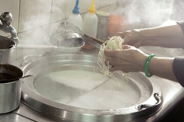 Closeup shot of a woman preparing the Chinese ramen noodles to be cooked in a cooking pot
