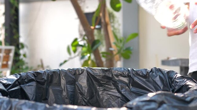 Hand of people sort waste plastic water bottles and throw them into the trash can to separate waste for recycle
