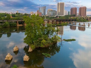 Small island with trees on the James River. In the distance is the downtown city skyline. Richmond, Virginia, United States.