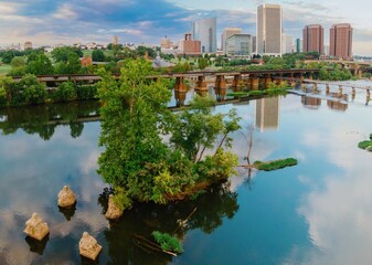 Obraz premium Small island with trees on the James River. In the distance is the downtown city skyline. Richmond, Virginia, United States.