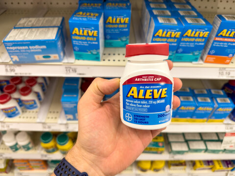 Holding a small bottle of Aleve pain relief medication.