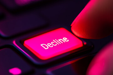 close up of finger tapping red Decline button on keyboard, symbolizing decision making and rejection. vibrant colors create striking visual impact