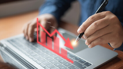 A person is typing on a laptop with a red downward arrow on the screen