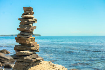 Stone tower at sunny sea coast beach balance harmony zen symbol. Natural pebble pyramid