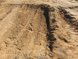 A cleared construction site. Tracks from the wheels of construction equipment, cars in the sand, soil. Background, place for text. 