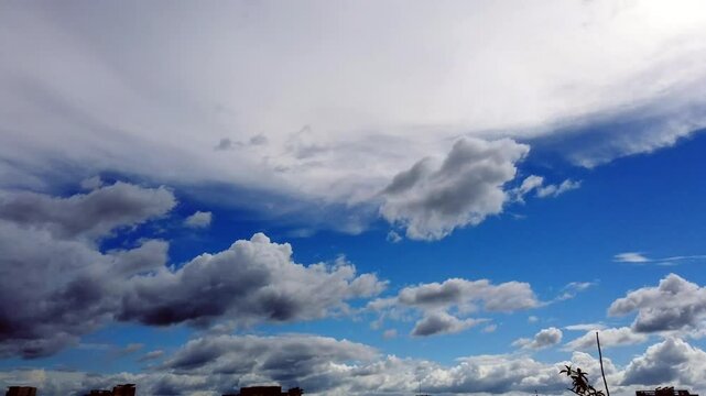 Time-lapse white and black Cloud in Blue sky. A thin city line in the bottom. Side to side two directional cloud movement. HD footage