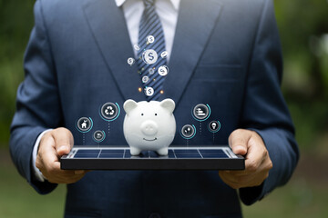 Businessman showing solar photovoltaics panels with piggy bank, Save money by using renewable...