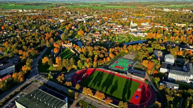 Aerial of the town of Dobele, Latvia in autumn, with an athletic field, houses, and trees