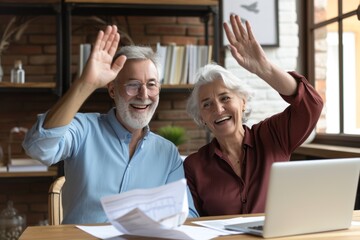 Excited older couple giving high five at home while celebrating a special moment during a sunny afternoon