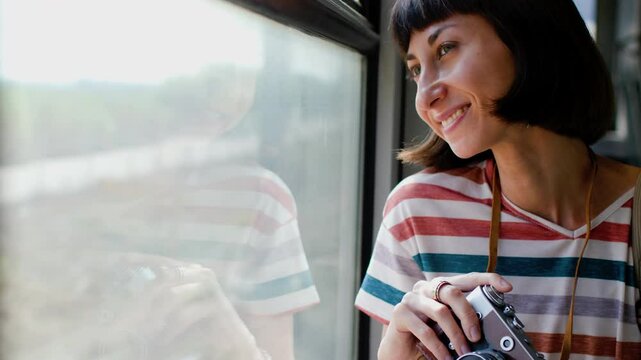 train travel. Young woman enjoying a train ride with a camera. tourist takes pictures of beautiful tourist places on camera. film camera. the girl uses a film camera.
