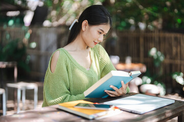 Beautiful asian young woman reading book education or learning on campus portrait outdoor happiness at university park