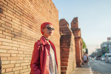 Fototapeta premium Gen z girl leather fashion with punk Asian woman tourist of local city Southeast Asia travel trendy pink hairstyle young female punk traveler walking around in town