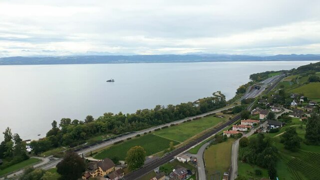 Pull back drone shot of Lake Neuchatel with grey sky in Vaumarcus in Canton of Neuchatel Switzerland