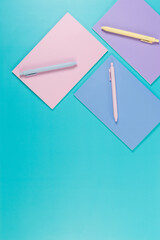 Top view of pink, purple and blue notebooks on blue background. Pink, yellow and blue pens, school, office wallpaper. Flat lay, copy space.