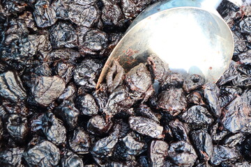 Deliciously dried black fruits presented elegantly with a shiny silver spoon as a gourmet treat
