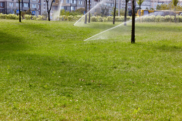 Automatic equipment for irrigation and maintenance of lawns, gardening in the autumn city park. Garden irrigation system watering lawn