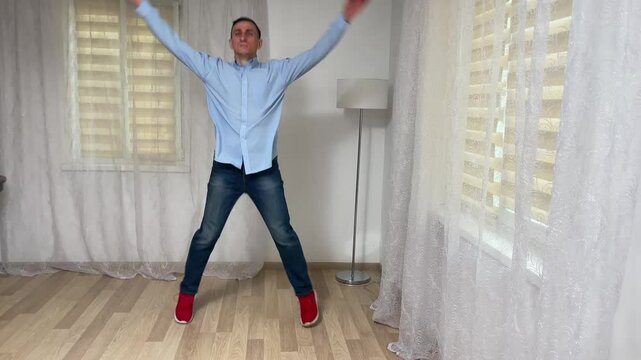 Man performing jumping jacks in a living room as part of a daily workout routine for fitness and health