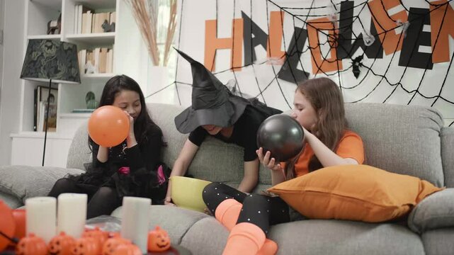 Children are blowing balloon and enjoy funny to prepare Halloween celebrate party  in living rom decorate with pumpkin head and spider web together.