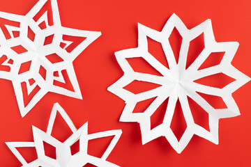 white paper cut out snowflakes in red background. winter or christmas theme background. selective focus.