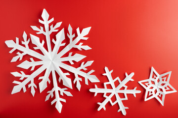 white paper cut out snowflakes in red background. Empty space for copy space. winter or christmas theme background. selective focus.
