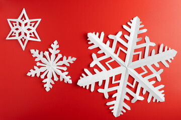 white paper cut out snowflakes in red background. winter or christmas theme background. selective focus.