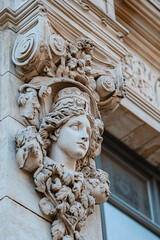 closeup of ancient stone carving on a building facade with a female statue and ornate details