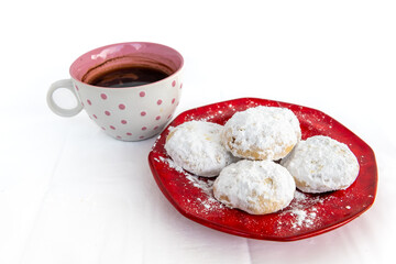 A plate of Kourabiedes, Greek butter cookies, with a cup of black coffee isolated in a white background.