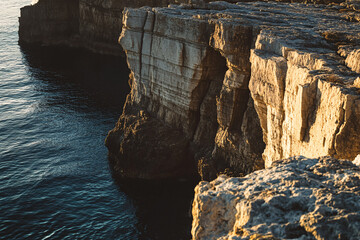 rugged coastal cliffs overlooking dark blue ocean water at sunset