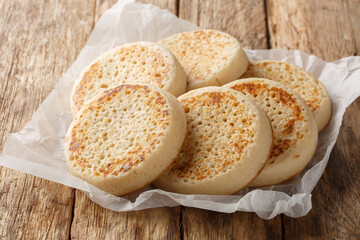 Porous Homemade English Crumpets close-up on parchment paper on old table. Horizontal