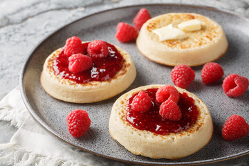English style crumpets served with berries jam and butter closeup on the plate on the table. Horizontal