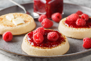 British Crumpets breakfast with butter and raspberry jam closeup on the plate on the table. Horizontal