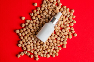 Plastic white tube for cream or lotion. Skin care or sunscreen cosmetic with chickpeas source of natural protein on red background.