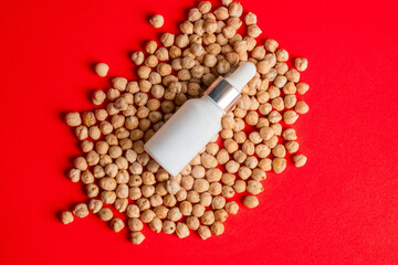 Plastic white tube for cream or lotion. Skin care or sunscreen cosmetic with chickpeas source of natural protein on red background.
