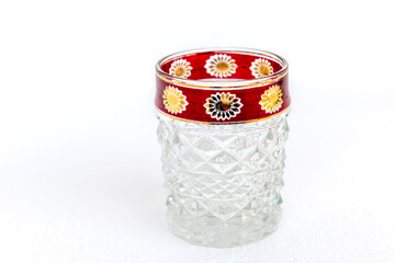 A vintage crystal glass cup with decorated rim, isolated on a white background.